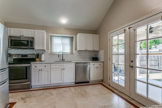 kitchen with lofted ceiling, appliances with stainless steel finishes, sink, and white cabinetry