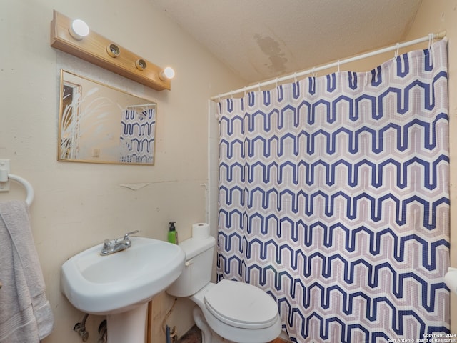 bathroom featuring curtained shower, sink, a textured ceiling, and toilet