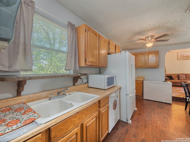 kitchen featuring ceiling fan, sink, white appliances, a textured ceiling, and dark hardwood / wood-style floors