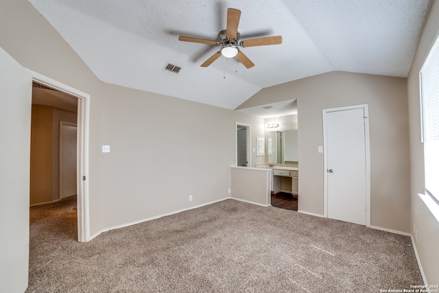 unfurnished bedroom featuring ceiling fan, vaulted ceiling, ensuite bathroom, and carpet