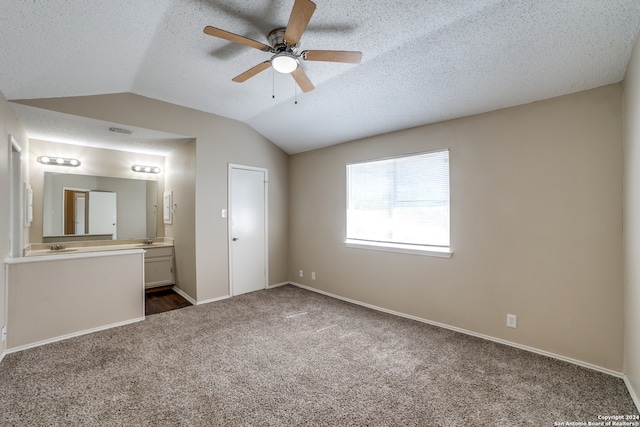 unfurnished bedroom featuring ceiling fan, a textured ceiling, vaulted ceiling, and dark carpet