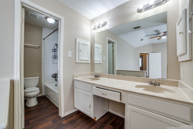 full bathroom with tiled shower / bath, vanity, a textured ceiling, hardwood / wood-style flooring, and toilet