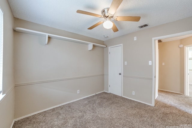 unfurnished bedroom featuring ceiling fan, light colored carpet, and a textured ceiling