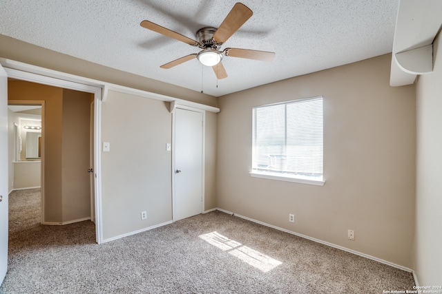 unfurnished bedroom featuring ceiling fan, carpet floors, a closet, and a textured ceiling