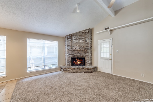 unfurnished living room featuring a brick fireplace, vaulted ceiling with beams, carpet floors, and a textured ceiling