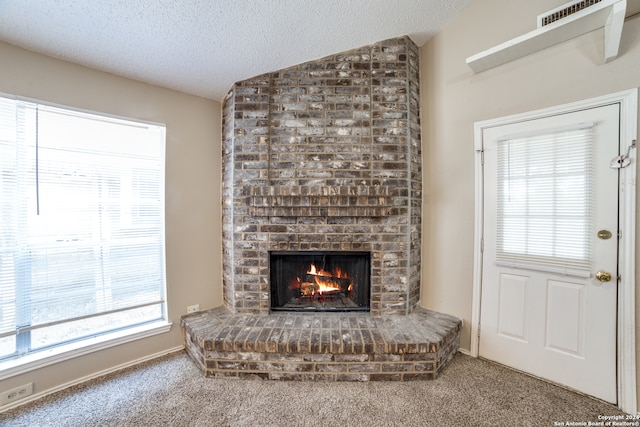 unfurnished living room featuring a fireplace, plenty of natural light, vaulted ceiling, and a textured ceiling