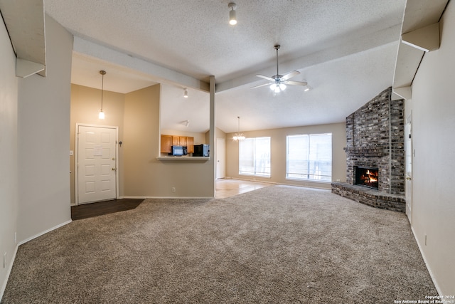 unfurnished living room featuring carpet, ceiling fan, beam ceiling, a fireplace, and a textured ceiling