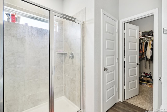 bathroom with hardwood / wood-style floors and a shower with shower door