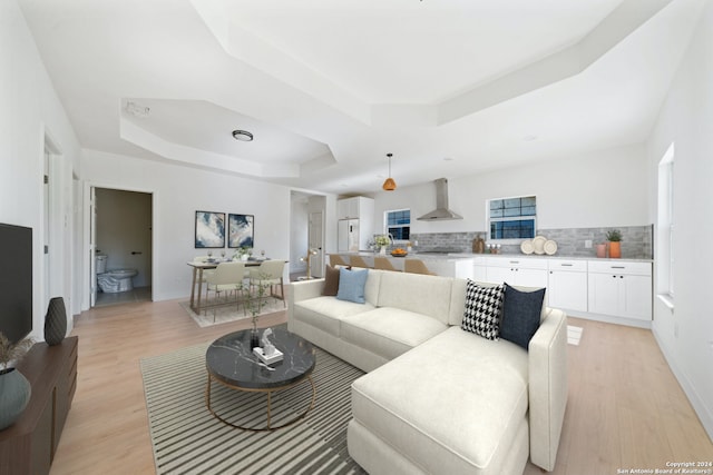 living room with a raised ceiling and light wood-type flooring