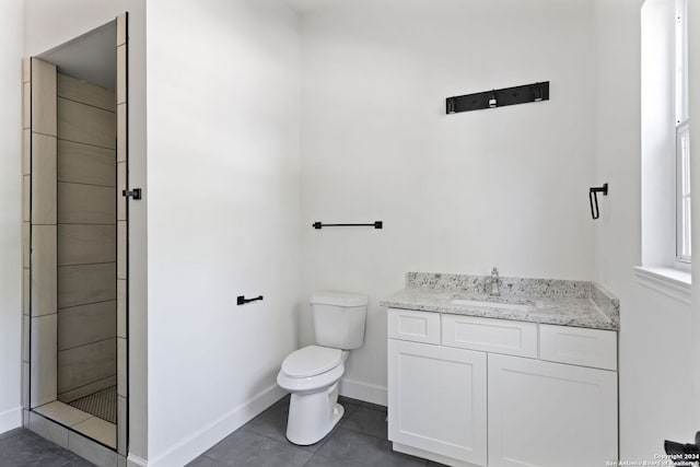 bathroom with tile patterned floors, vanity, a tile shower, and toilet