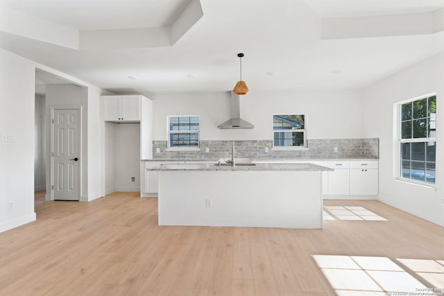 kitchen with white cabinets, pendant lighting, light stone counters, and wall chimney exhaust hood