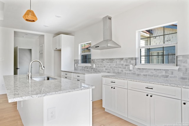 kitchen featuring ventilation hood, sink, pendant lighting, white cabinets, and an island with sink