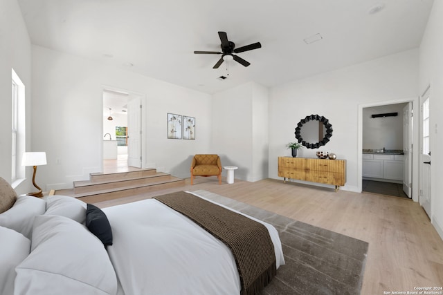 bedroom with ensuite bathroom, ceiling fan, and light hardwood / wood-style floors