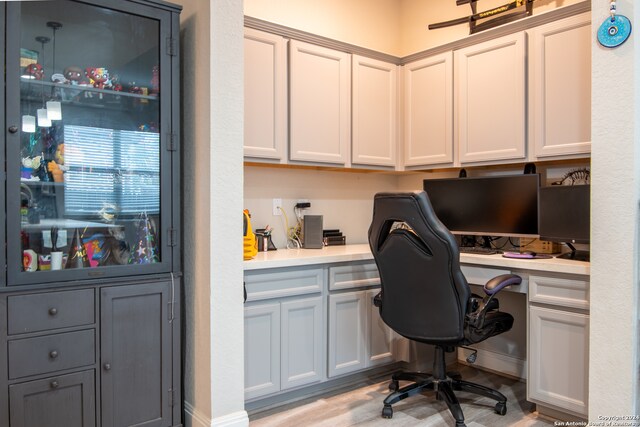 office space with built in desk and light hardwood / wood-style flooring