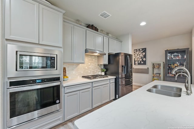 232 Wickersham, Boerne, TX 78015 - kitchen featuring decorative backsplash, visible vents, stainless steel appliances, a sink, and under cabinet range hood