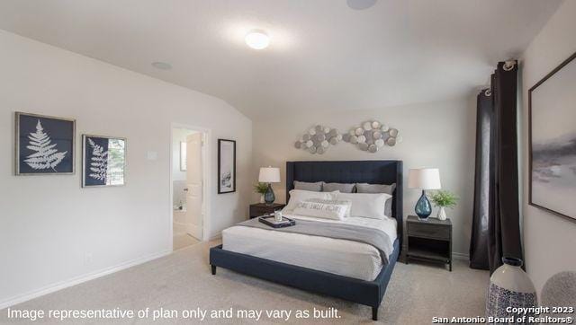 carpeted bedroom with ensuite bath, vaulted ceiling, and baseboards