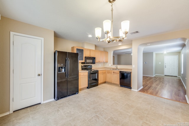 kitchen with light wood-type flooring, black appliances, sink, light brown cabinetry, and decorative light fixtures