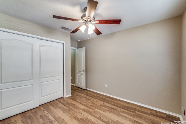 unfurnished bedroom with ceiling fan, a closet, and light hardwood / wood-style floors