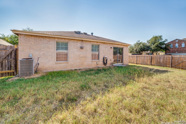 rear view of property with a lawn and central air condition unit