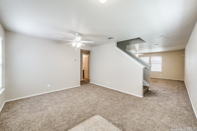 unfurnished living room with light carpet, a textured ceiling, and ceiling fan