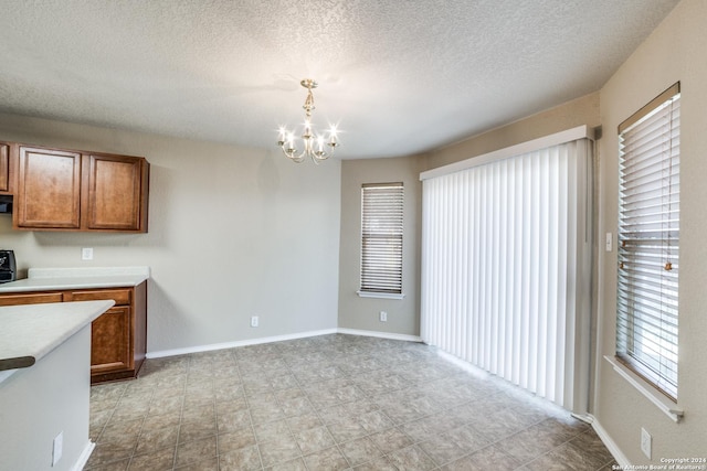 2815 Bandbury Oak, San Antonio, TX 78247 - unfurnished dining area with a chandelier, plenty of natural light, a textured ceiling, and baseboards