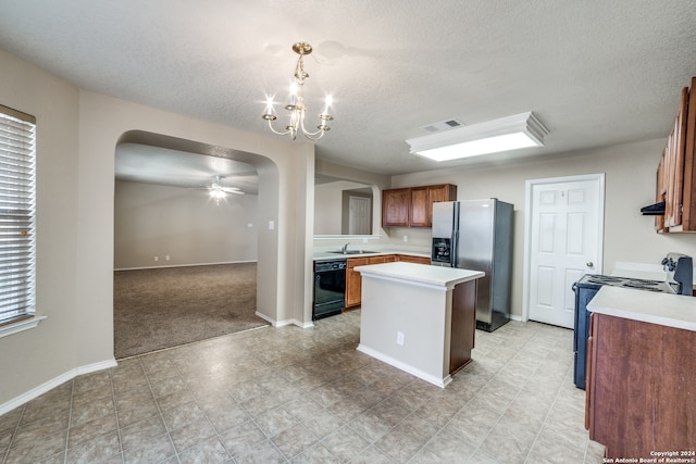 kitchen featuring pendant lighting, ceiling fan with notable chandelier, sink, black appliances, and a center island