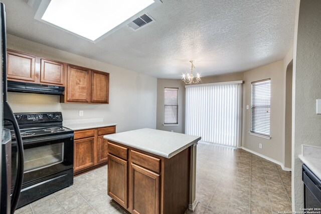 kitchen featuring black appliances, a center island, pendant lighting, an inviting chandelier, and a textured ceiling