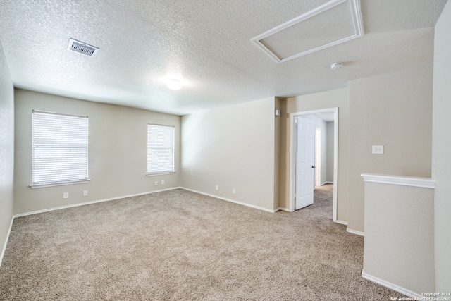 unfurnished room with light colored carpet and a textured ceiling