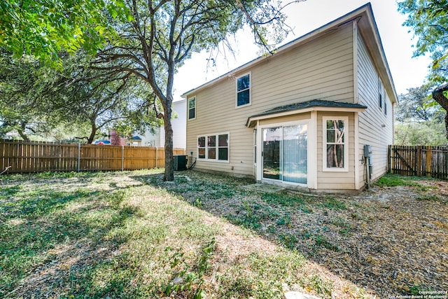 rear view of property with cooling unit and a lawn