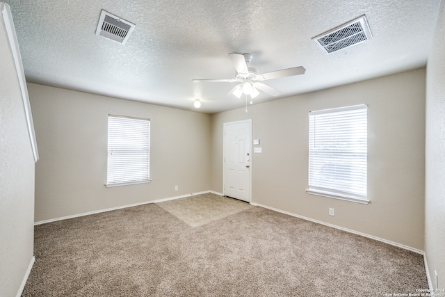 carpeted empty room featuring ceiling fan and a textured ceiling