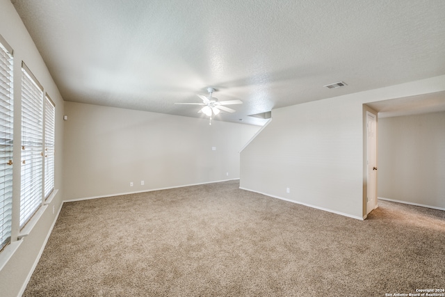 carpeted spare room with ceiling fan and a textured ceiling