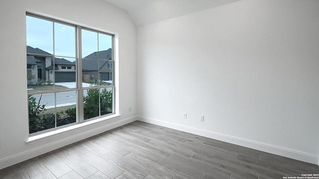 unfurnished room with vaulted ceiling and wood-type flooring