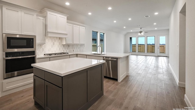 kitchen with sink, a center island, kitchen peninsula, stainless steel appliances, and white cabinets