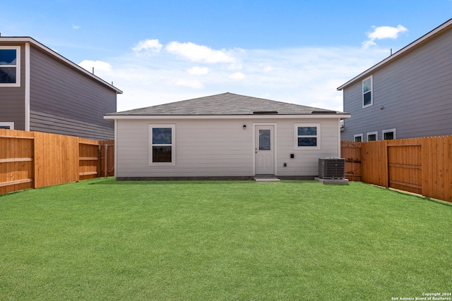 back of property with central AC unit and a lawn