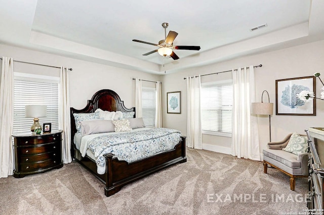 bedroom featuring light carpet, ceiling fan, and a raised ceiling