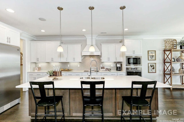 kitchen featuring an island with sink, white cabinets, decorative light fixtures, and built in appliances