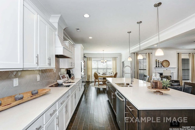 kitchen featuring white cabinets, an island with sink, pendant lighting, sink, and dark wood-type flooring