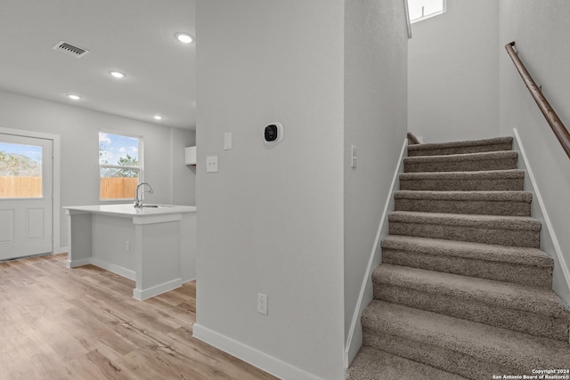 stairs featuring hardwood / wood-style floors and sink