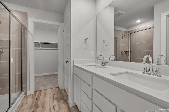 bathroom with hardwood / wood-style flooring, vanity, and a shower with door