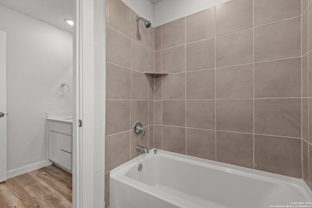 bathroom with hardwood / wood-style floors, vanity, and tiled shower / bath