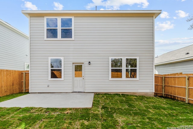 back of property with a yard and a patio