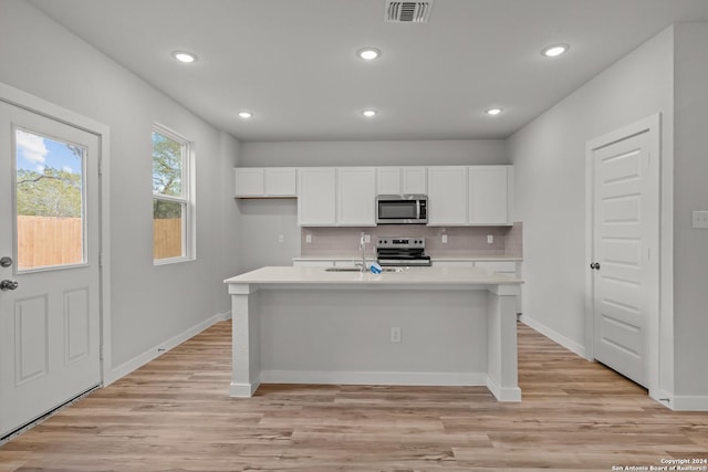 kitchen featuring white cabinetry, an island with sink, stainless steel appliances, and light wood-type flooring