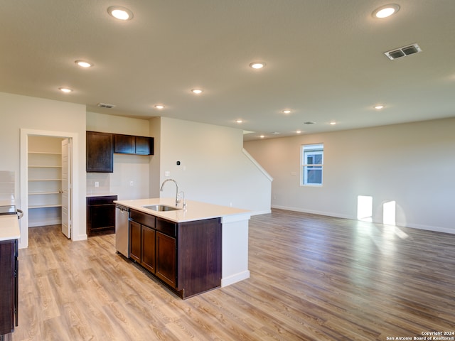 kitchen with sink, light hardwood / wood-style flooring, stainless steel dishwasher, a kitchen island with sink, and dark brown cabinets