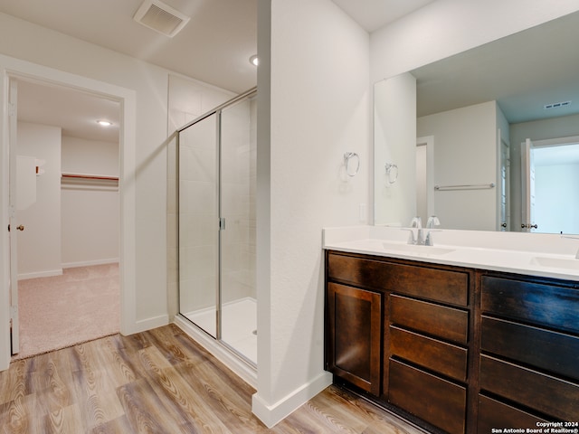 bathroom with hardwood / wood-style flooring, vanity, and walk in shower