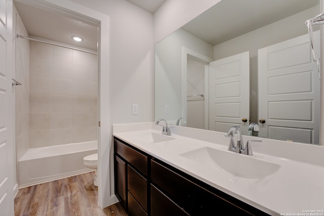 full bathroom with vanity, wood-type flooring, tiled shower / bath combo, and toilet