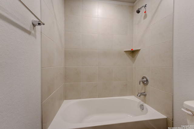 bathroom with toilet and tiled shower / bath