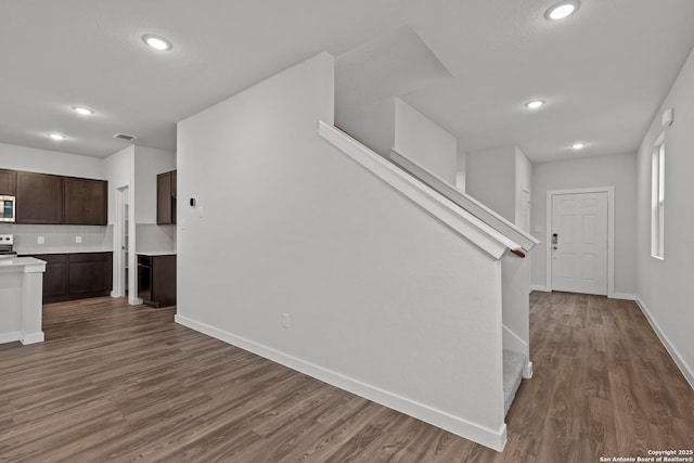 interior space featuring recessed lighting, dark wood-type flooring, baseboards, and stairs