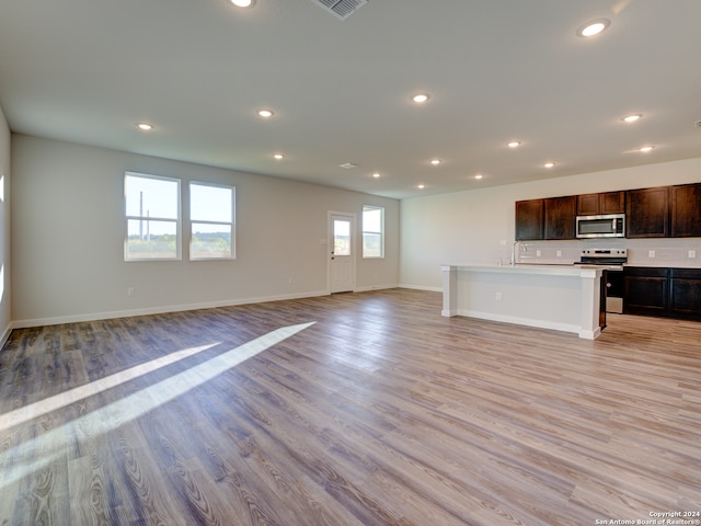 kitchen featuring plenty of natural light, light hardwood / wood-style floors, an island with sink, and appliances with stainless steel finishes