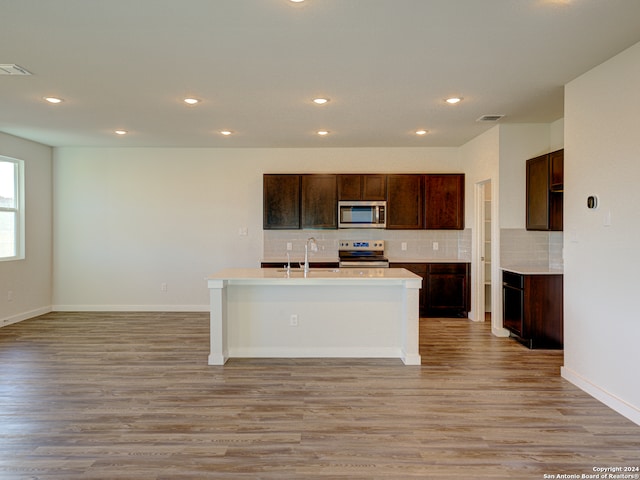 kitchen featuring stainless steel appliances, light hardwood / wood-style flooring, a center island with sink, and sink