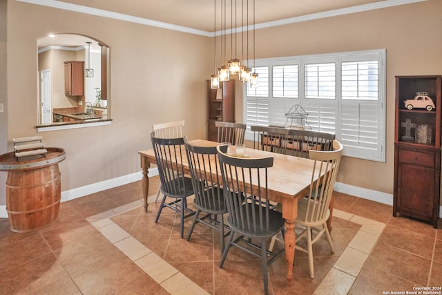 tiled dining space featuring sink, crown molding, and a chandelier